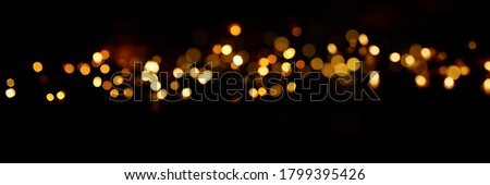 Black background with golden light effects. Horizontal background with blur bokeh effects for christmas time. Special occasion concept with space for text. Royalty-Free Stock Photo #1799395426