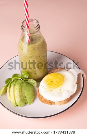 healthy breakfast of smoothies, avocado and toast with egg on a pink background
