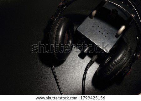 The full size headphones are placed with a tube preamp on a black background.