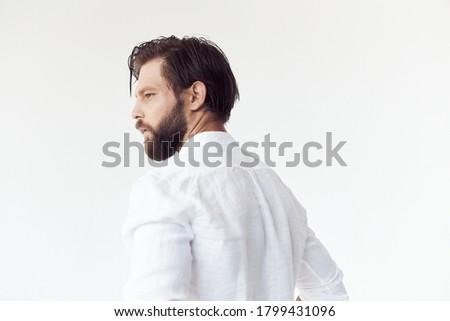 portrait photo of a handsome bearded man with brown hair on white background, he is wearing a white linen shirt, he looks away 