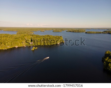 Aerial view of cottage country with docks and boats at lakes surrounded by green forests. Blue sky, sunny summer day. Ontario, Canada, North America.