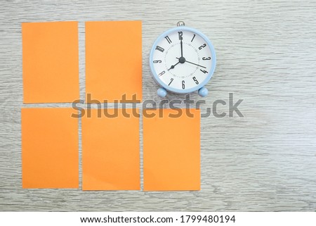 Alarm clock and blank notes on wooden table 