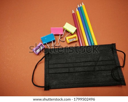Prevention of COVID-19 while returning to school, new normal concept with school supplies,  black striped cloth mask.
