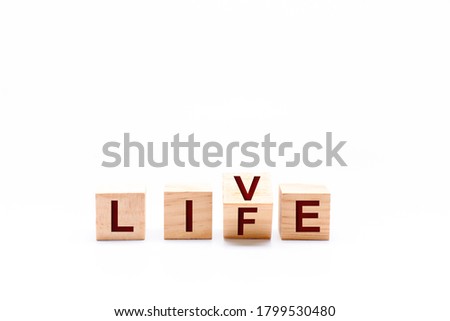 Spinning wooden dice by changing the word LIFE to LIVE. White background