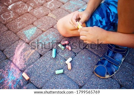 Blurred image Multi-colored chalk in a child's hand close-up. The concept of joy, positive, good mood and happiness. Blurred image, selective focus. No focus.