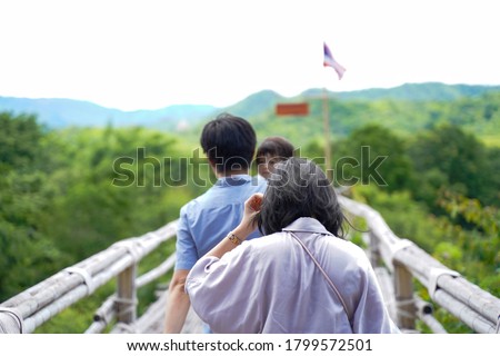 Back view of Young Asian Family with baby on blur backgroundd of top beautiful view of rainforest ,Parents and children while walking on the bamboo bridge with sunlight in morning in Thailand. Royalty-Free Stock Photo #1799572501