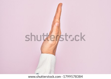 Hand of caucasian young man showing fingers over isolated pink background showing the side of stretched hand, pushing and doing stop gesture