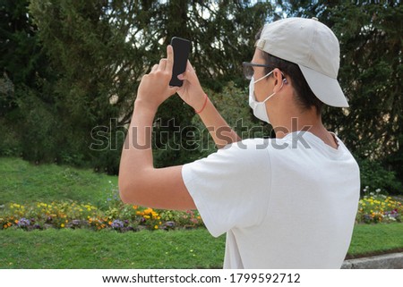 young man taking a photo in the gardens of san ildefonso in Segovia on a summer holiday concept