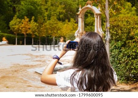 girl taking pictures with her camera during the visit of the gardens and fountains in La Granja de San Ildefonso Palace 18th century Royal Palace in the province of Segovia in Spain on a summer day