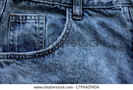 Details of denim trousers. Pockets and seams on denim.Old blue denim.The texture of the fibers of the denim. Background.
