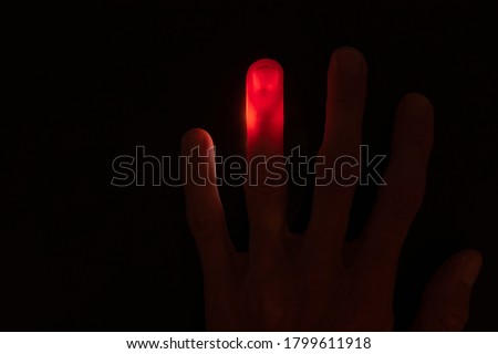 Abstract background of Illuminated and transparent red finger with visible vein on black background with copy space