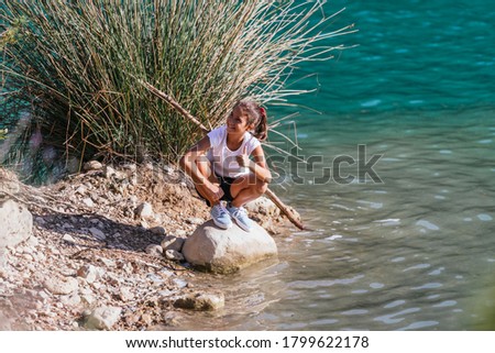 A girl smiling on top of a rock next to the swamp and with thumbs up