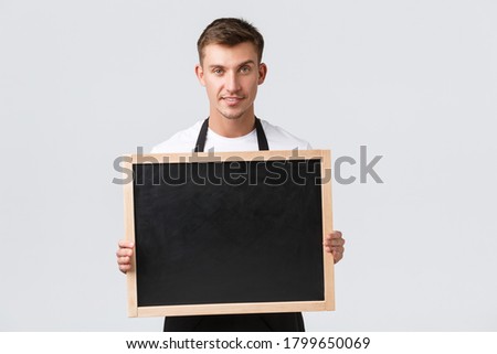 Small retail business owners, cafe and restaurant employees concept. Friendly good-looking salesman announce something to clients, holding board without signs, smiling happy, white background