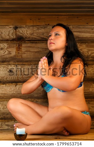 Young brunette woman sits in a bath with a light meditates.