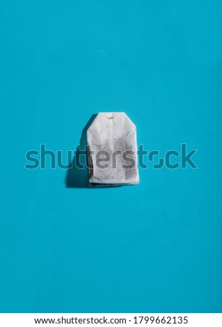 Tea bag on a blue background. Hard shadow.
place for an inscription. Photograph with copy-space.