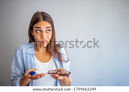 woman hold contact lenses and glasses in hands close up. concept of choice of vision protection. Girl holding glasses in one hand and contact lens other hand. Girl Comparing Contacts to Eyeglasses  Royalty-Free Stock Photo #1799662249