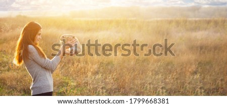 a young woman with red hair and a gray foot, Caucasian appearance, holds a cute fluffy Easter bunny in front of a stob with a place for your text, photo banner. Spring Holidays Concept