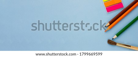 Colored pencils and notes on a blue background. Photo banner. Place for your text. Education concept.