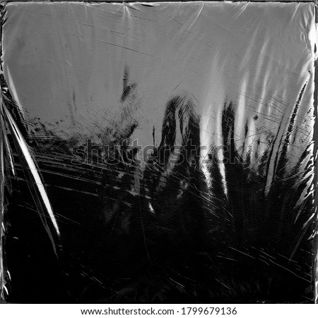 Wrinkle transparent shiny plastic wrap overlay on black background Royalty-Free Stock Photo #1799679136