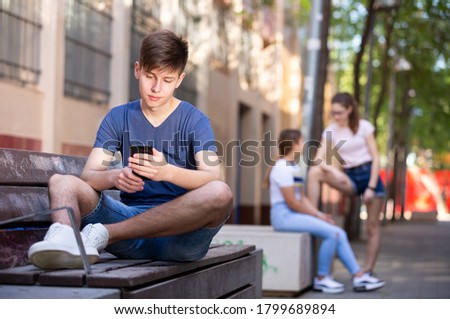 Portrait of teenage boy absorbed in online chat on mobile phone. Concept of youth addiction of social networks