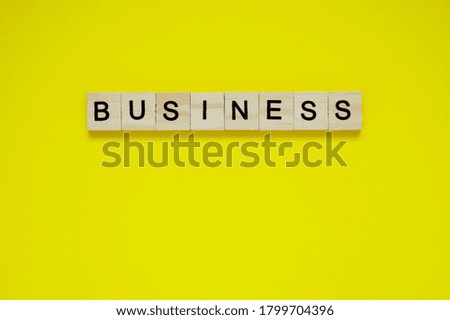 Word business. Top view of wooden blocks with letters on yellow surface
