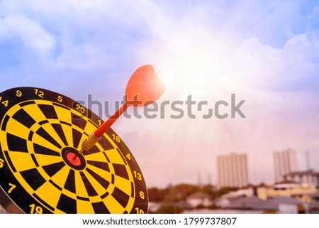 Red dart arrow hit in the target center of dartboard with sky background, Target hit in the center by arrows