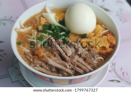 Batchoy or batsoy, a noodle soup in Philippines made with pork offal, crushed pork cracklings, chicken stock, beef loin and round noodles. Shallow depth-of-field. 