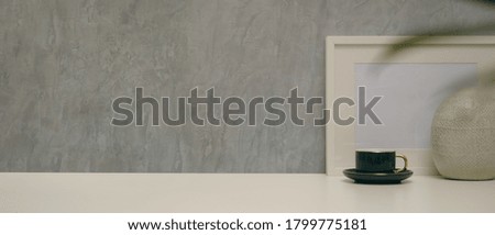 Close up view of modern home interior design with copy space, mock up frame, vase and cup on desk with loft wall