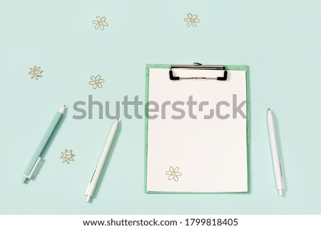 Flat lay with  office supplies, paper tablet with clip, blue and white colored pens, ruler and metal paper clips. School and education concept. View from above and copy space.
