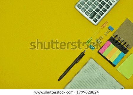top view of colorful stationery equipments,calculator and face mask on yellow background,back to school concept.