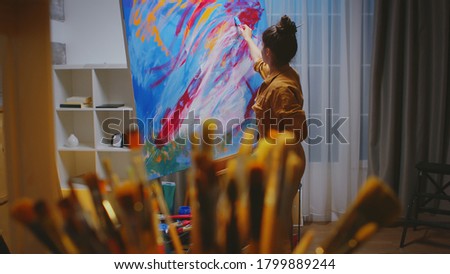 Artist choosing the right paint brush in art studio for her masterpiece.