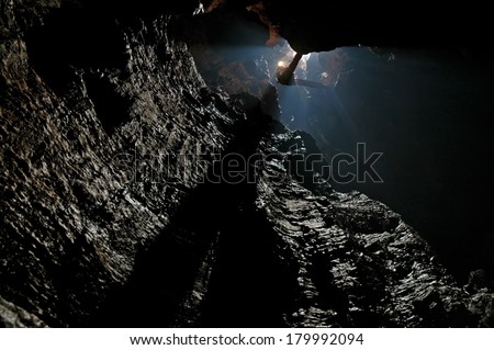 Caver, spelunker abseiling in a deep pothole  Royalty-Free Stock Photo #179992094