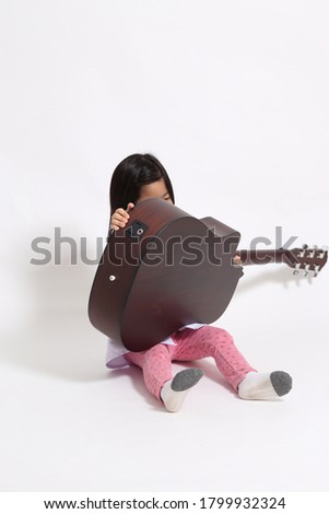 The young Asian girl with acoustic guitar on the whit background.