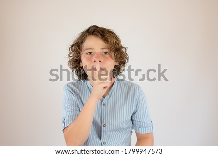 Boy with blue shirt making a silence gesture