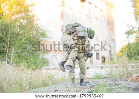 A military man carries his wounded partner during combat operations. A soldier's friend saves his comrade. Patriotism, loyalty, bravery. An accident during the war. Royalty-Free Stock Photo #1799955469