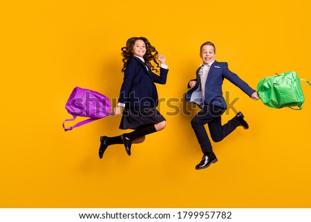 Full length body size view of his he her she attractive glad small little cheerful kids jumping having fun new academic year semester isolated bright vivid shine vibrant yellow color background