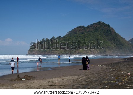 Suwuk beach landscape, people on vacation with a background of hollow coral hills and blue sky