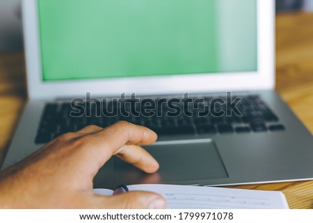 Business person using touchpad of laptop with green screen.