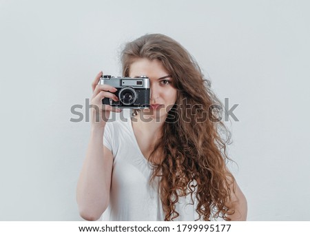 Curly woman takes pictures on an old film camera. Holds a camera in her hand.