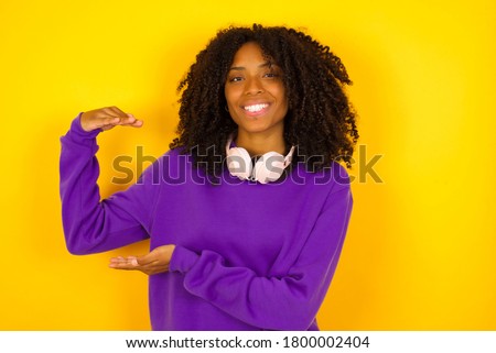 African American woman over isolated background gesturing with hands showing big and large size sign, measure symbol. Smiling looking at the camera. Measuring concept.