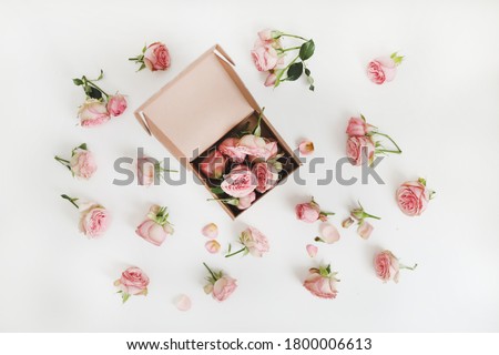 Craft gift box and flowers. Roses in a box  close-up with a floral background on a white table. Open gift box on a desktop with flowers, online shopping and fashion concept
