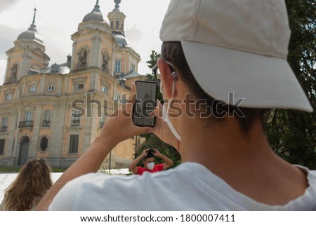 young man with a cloth visor taking a photo of a building in the gardens of San Ildefonso in Segovia on a summer day concept holiday