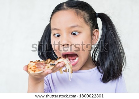 cute little girl holds piece of pizza, hungry student opens mouth wide while sees delicious slice of pizza, wants to eat