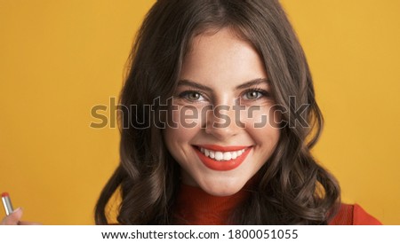 Portrait of cheerful pretty brunette girl with red lips happily looking in camera over colorful background  