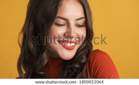 Close up charming brunette girl with red lips happily smiling on camera over colorful background  