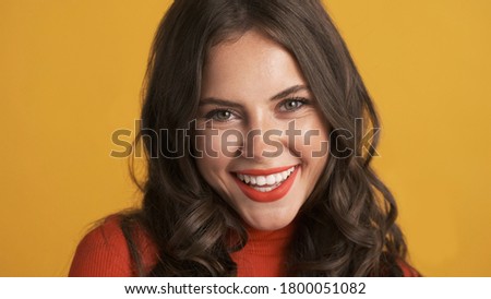 Portrait of beautiful smiling brunette girl with red lips joyfully looking in camera over colorful background  