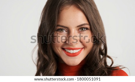 Beautiful smiling brunette girl with red lips happily looking in camera over white background