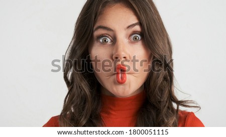Portrait of pretty brunette girl fooling around on camera over white background. Fish expression