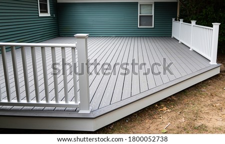 New composite deck on the back of a house with green vinyl siding.with whie railings. Royalty-Free Stock Photo #1800052738