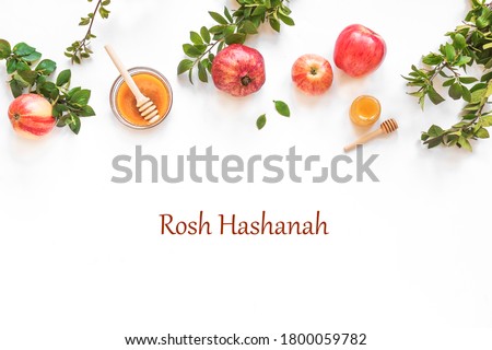 Rosh Hashanah jewish New Year holiday concept banner. Creative layout of traditional symbols - apples, honey, pomegranate isolated on white, top view, copy space. Royalty-Free Stock Photo #1800059782